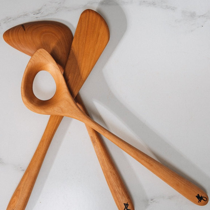Two wooden spoons and a wooden spatula on a marble background.