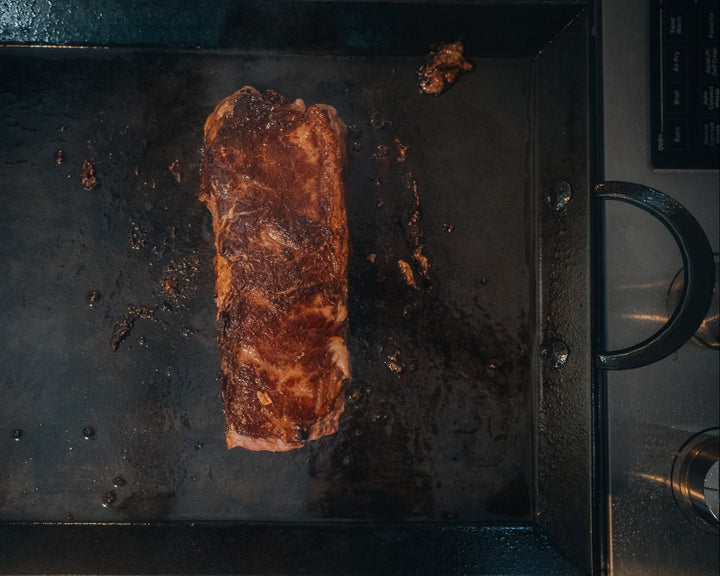 Grilled steak on a hot carbon steel griddle