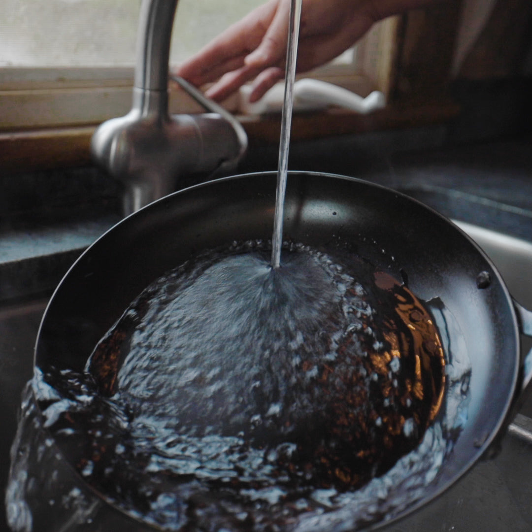 Cook rinsing carbon steel skillet in sink