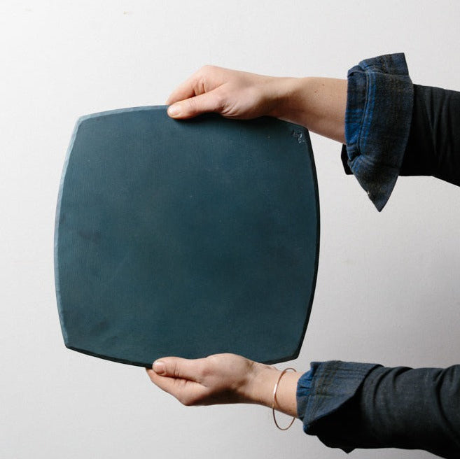 Two hands holding a handmade carbon steel bakeware sheet