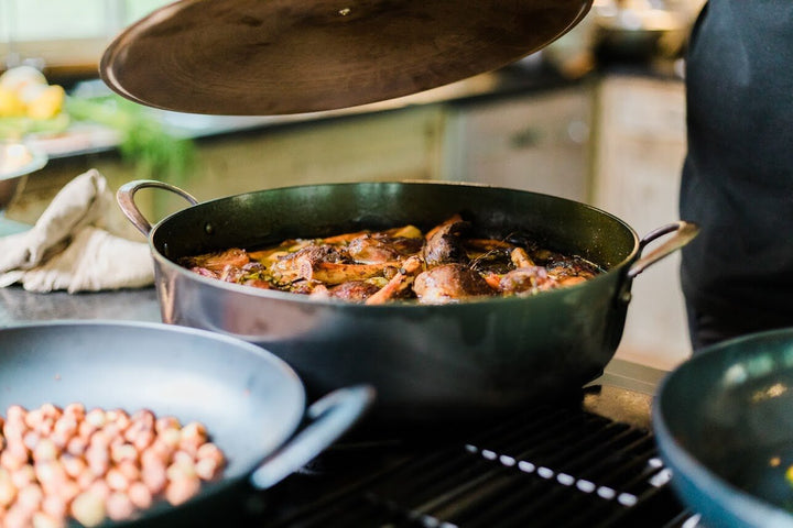 Chicken stewing in hand forged, artisan carbon steel pro rondeau pot with a stainless steel lid