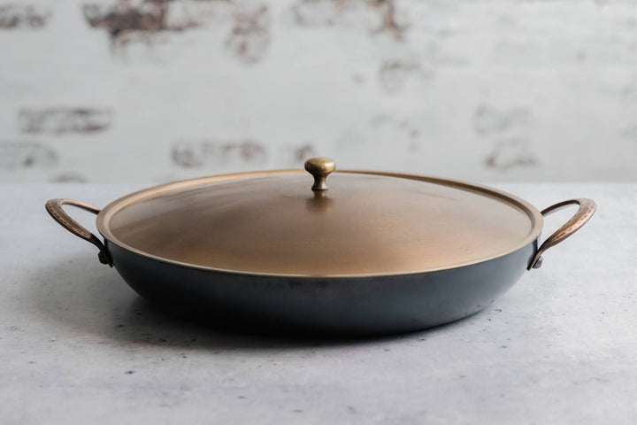 Handcrafted carbon steel saucier with bronze handles and stainless steel lid