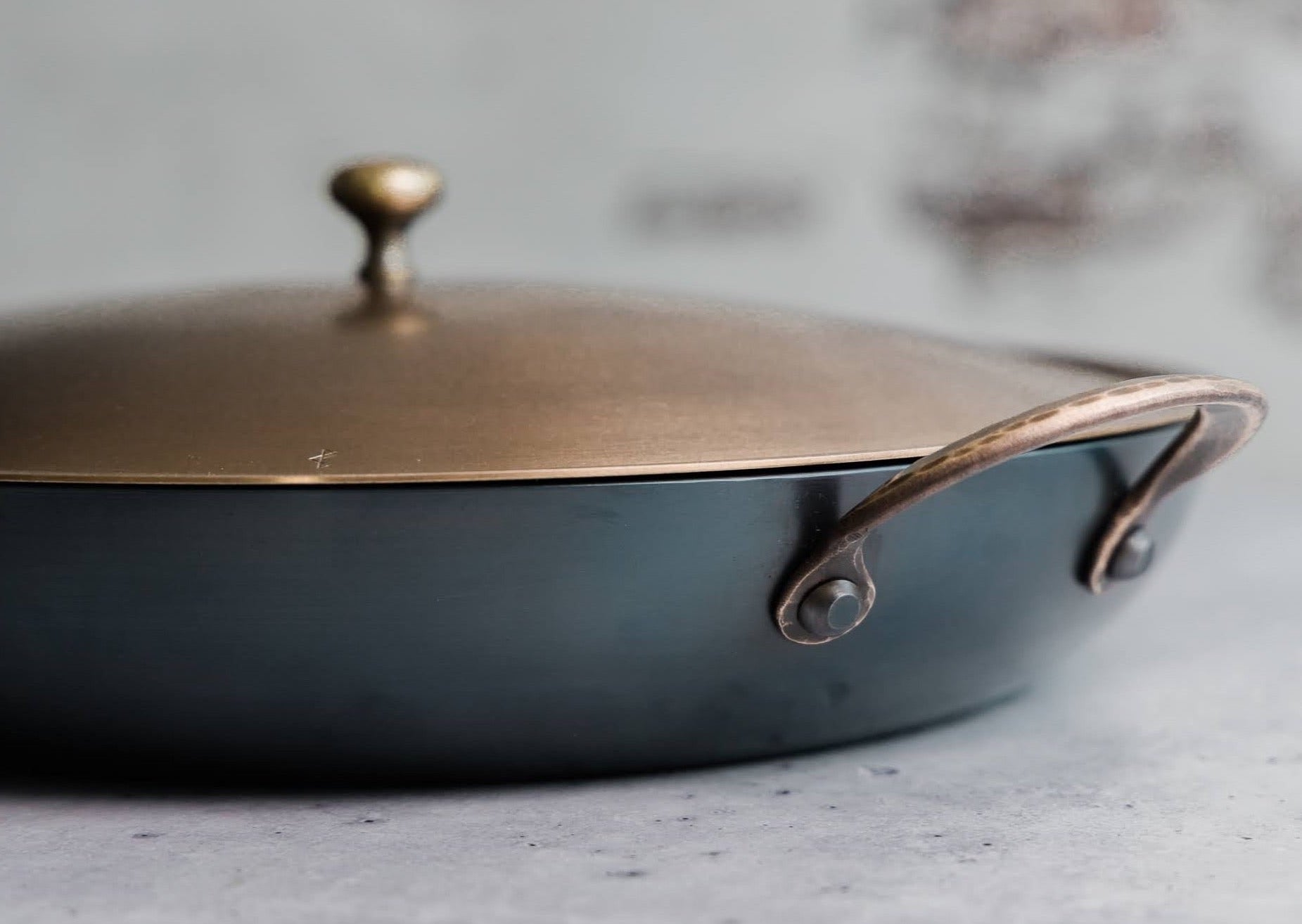 Handcrafted carbon steel saucier with bronze handles and stainless steel lid