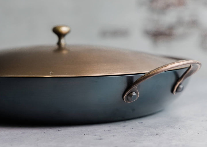 Handcrafted carbon steel saucier with bronze handles and stainless steel lid