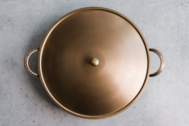 Handcrafted carbon steel saucier with bronze handles and stainless steel lid