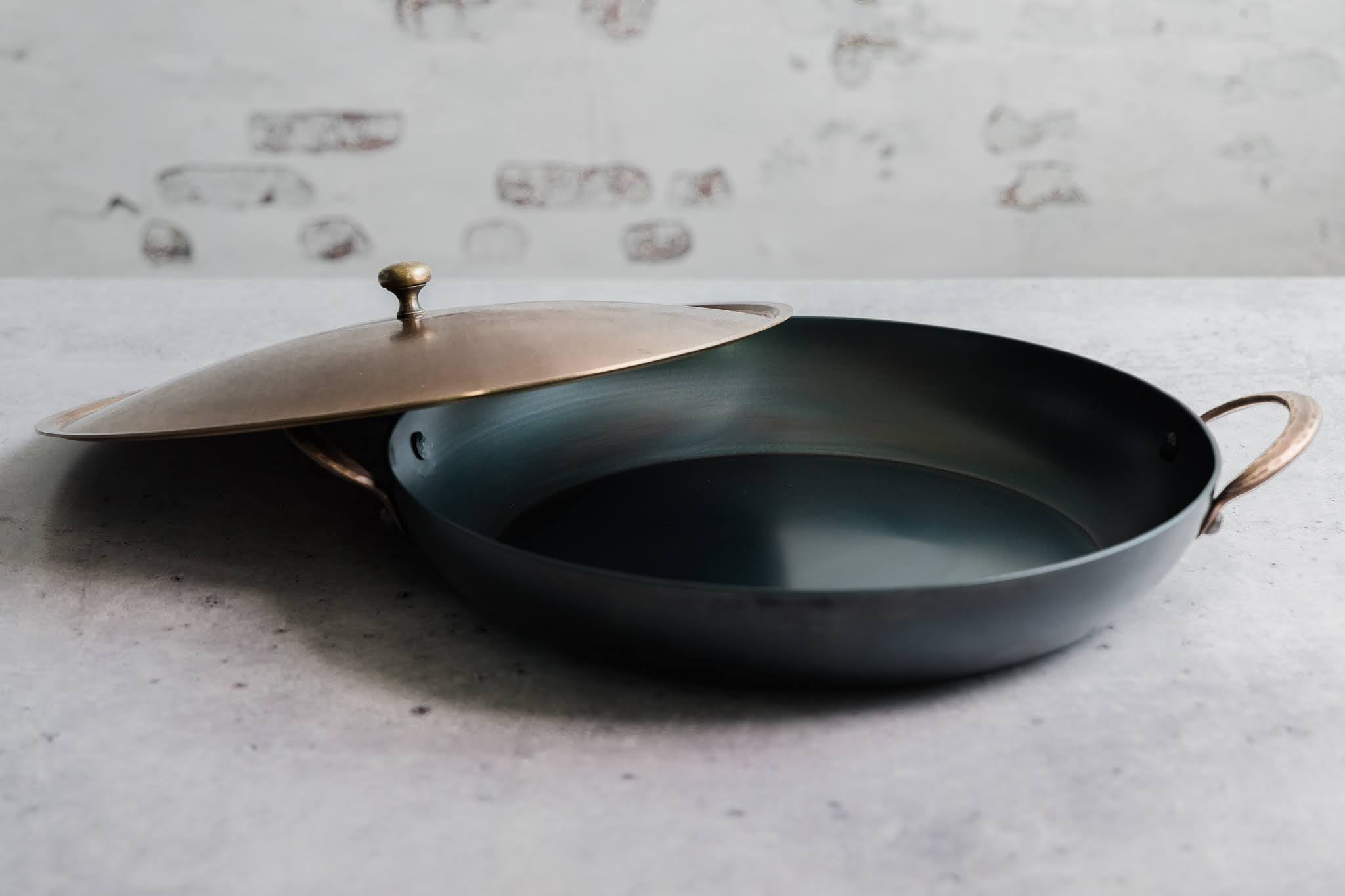 Handcrafted carbon steel saucier with bronze handles and stainless steel lid