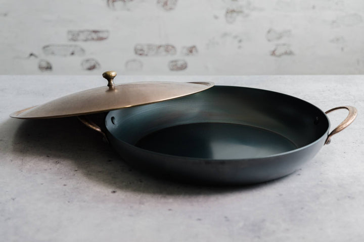 Handcrafted carbon steel saucier with bronze handles and stainless steel lid