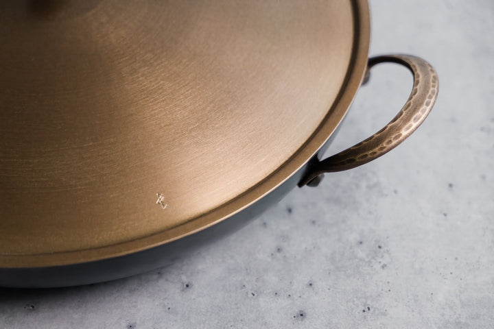 Handcrafted carbon steel saucier with bronze handles and stainless steel lid