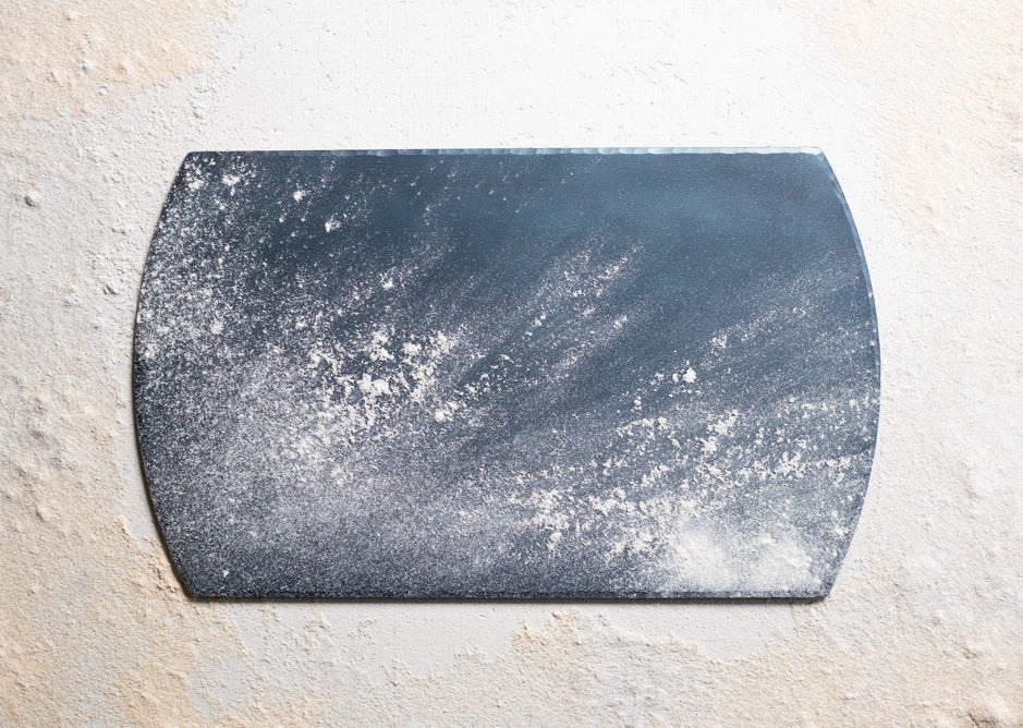 A handmade, hand forged carbon steel bakeware sheet powdered in flour