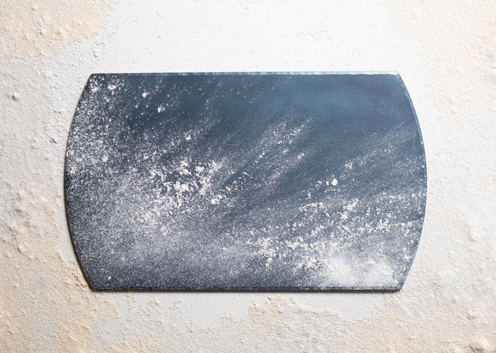 A handmade, hand forged carbon steel bakeware sheet powdered in flour