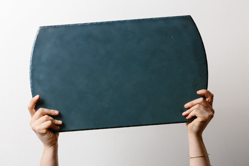 Two hands holding a handcrafted long, carbon steel bakeware sheet