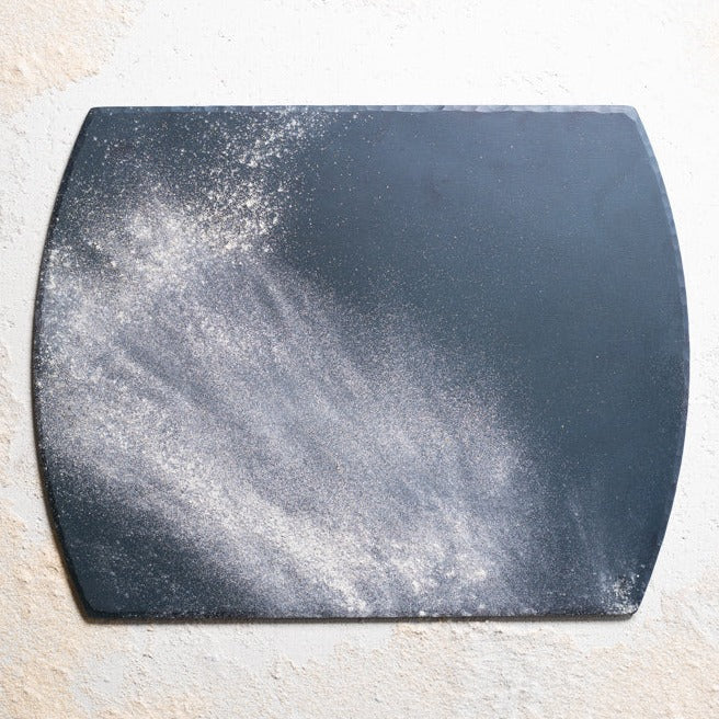 A handmade, hand forged steel bakeware sheet powdered in flour