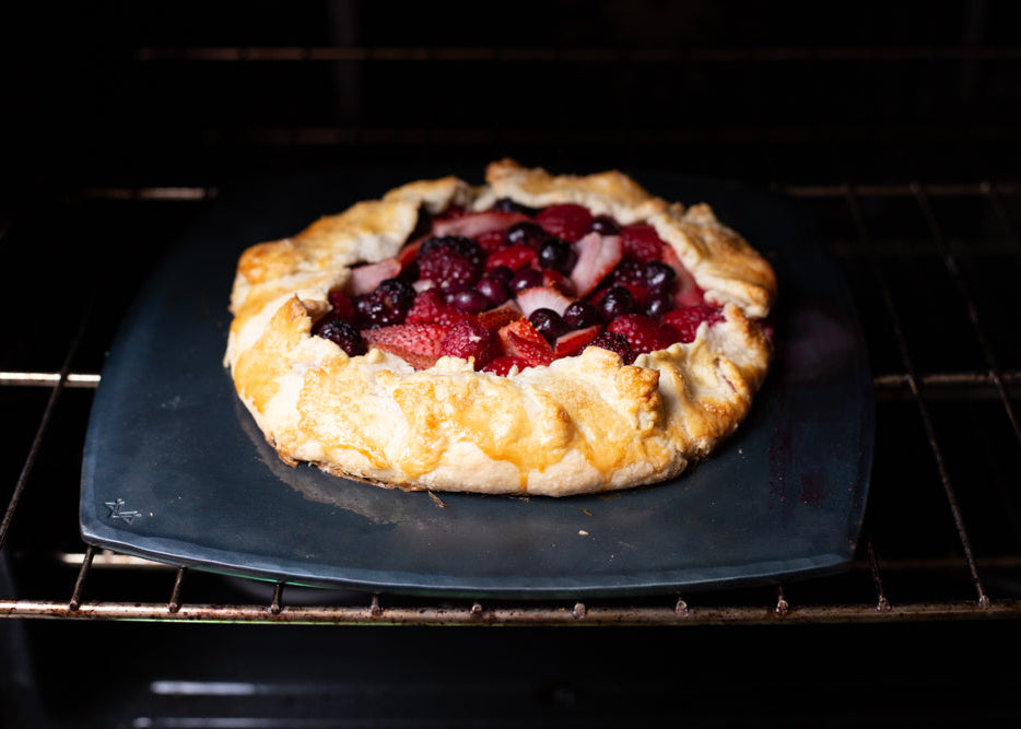 A handcrafted carbon steel square bakeware on an oven rack with a handmade berry tart on top