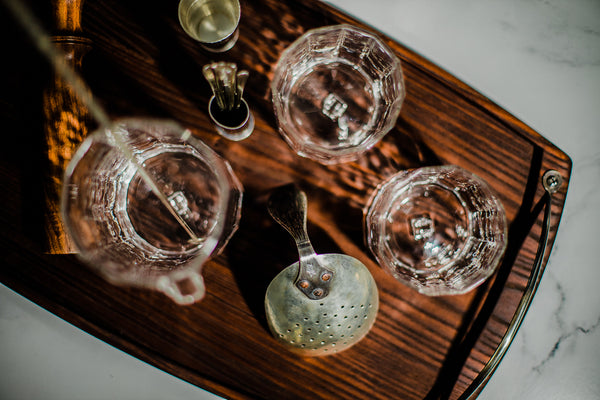 A birds eye view of a handmade cocktail tray with handmade cocktail glasses, hand forged cocktail spoon, hand forged strainer and handmade cocktail mixing glass