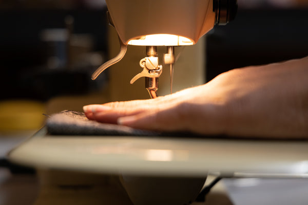 Hands guiding material through a sewing machine
