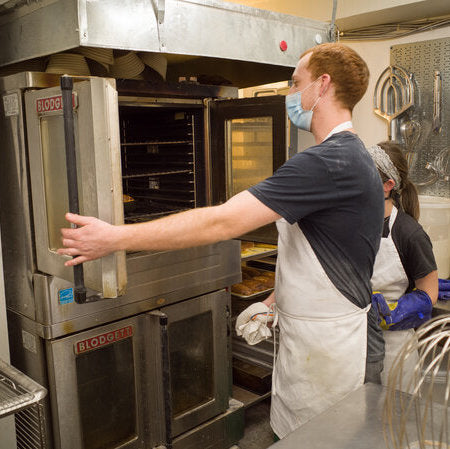 Baker closing an industrial oven in a bakery kitchen 