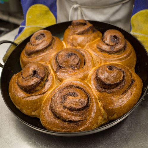 Baked cinnamon rolls in a carbon steel saucier pan