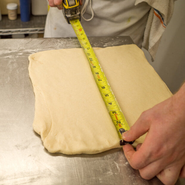 Baker measuring out dough on a stainless steel surface