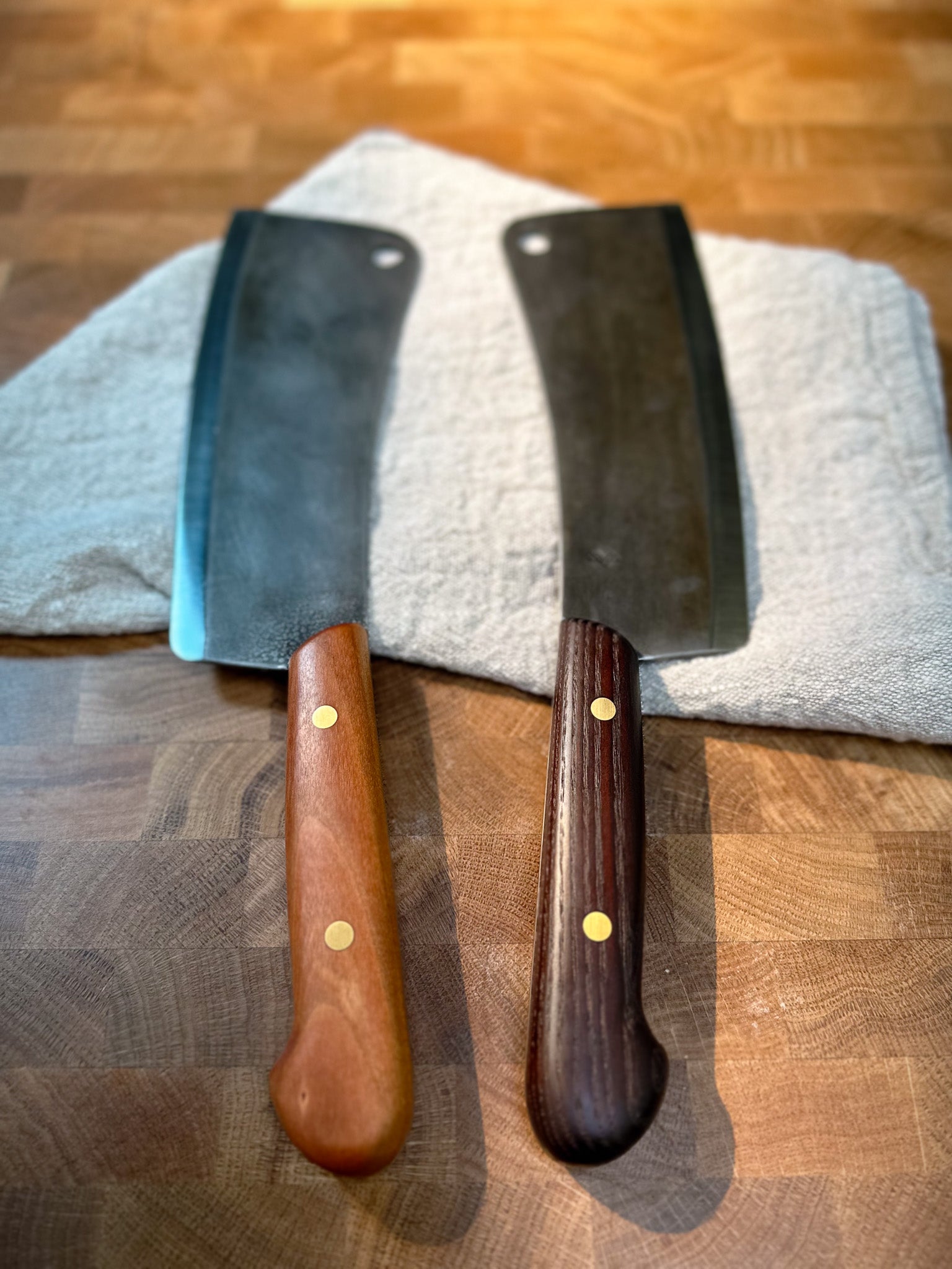 Two cleavers with wooden handles on a wooden surface