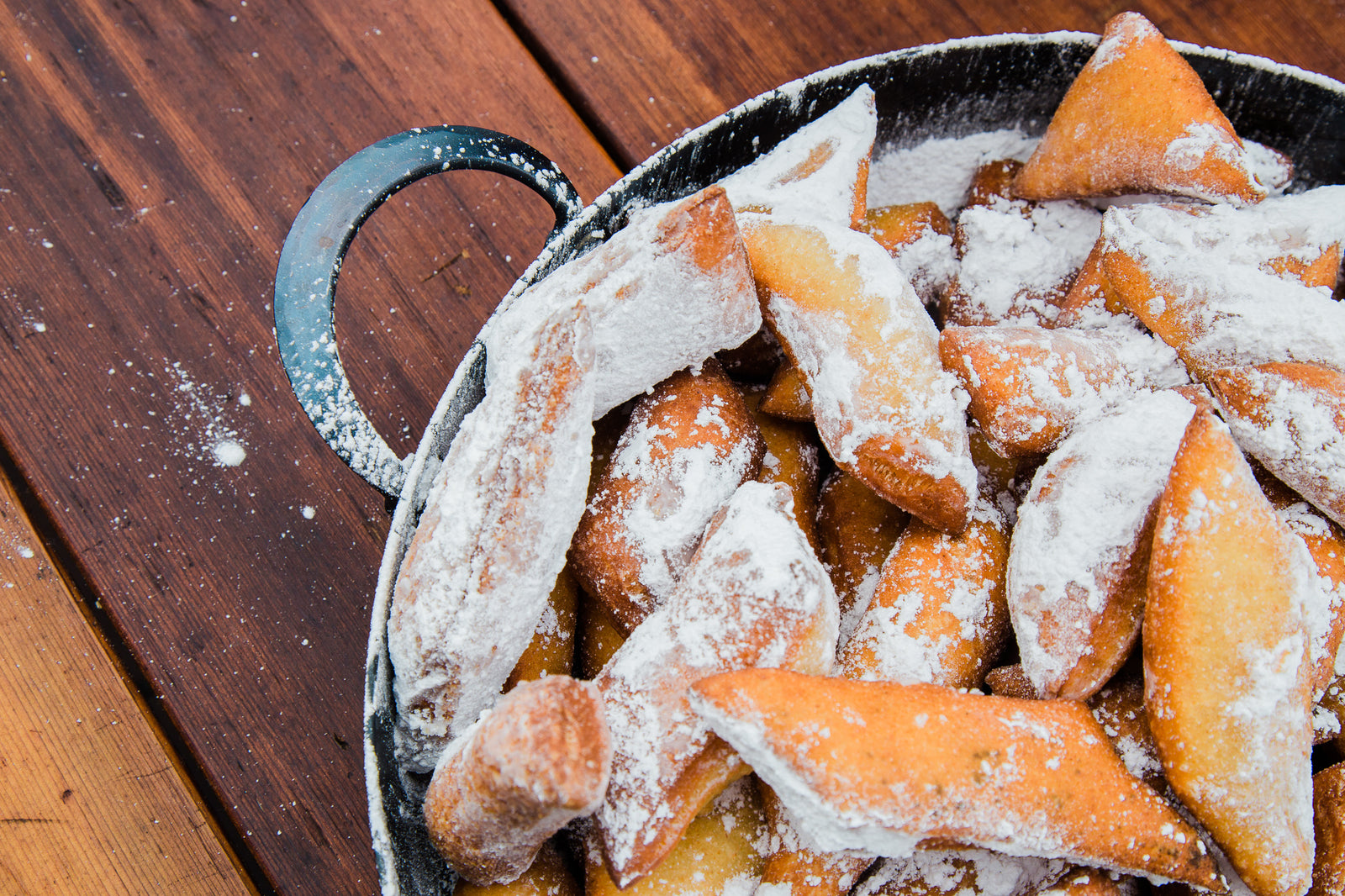Hand forged carbon steel saucier holding powdered beignets 