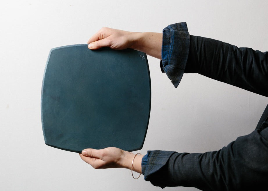 Two hands holding a handmade carbon steel bakeware sheet