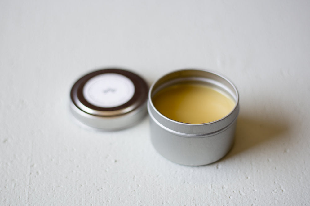 Open homemade wood balm container on cement surface